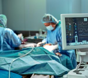 Team of surgeons for work in the operating room. Several surgeons are doing an operation in a real operating room. Blue light, white gloves vertical shot